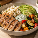 Chicken rice bowl with avocado, roasted vegetables and a light herb sauce